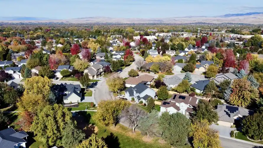 Another aerial view of the neighborhood showing multicolored tree canopy and well-maintained homes.